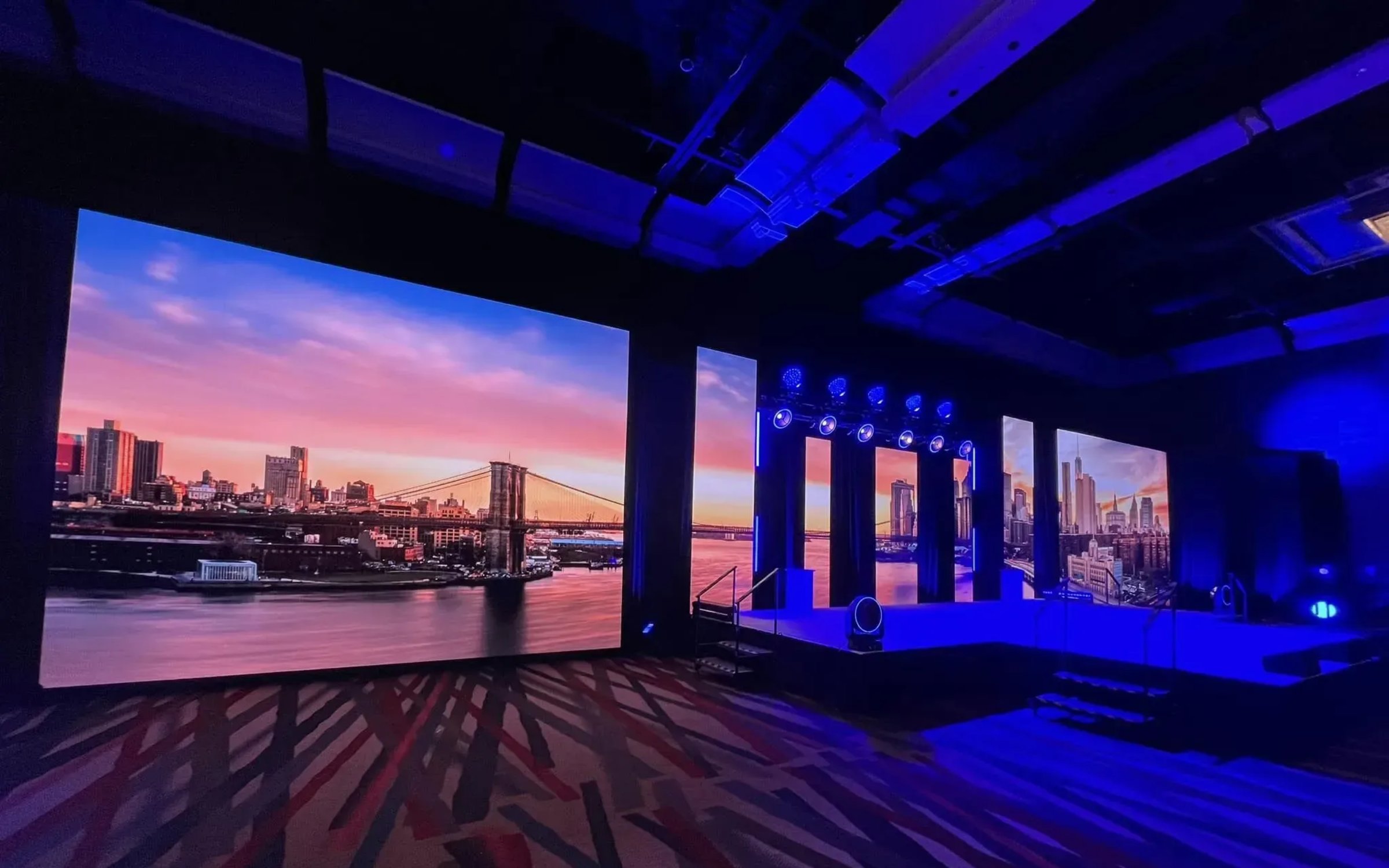 Multi-panel LED wall installation in ballroom with cityscape content and blue accent lighting