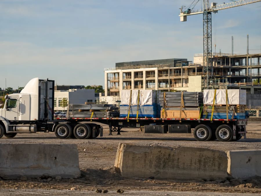 A flatbed truck loaded with building materials parked at an active construction site