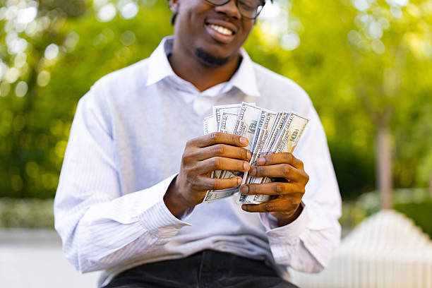 A man holding wads of money from a windfall
