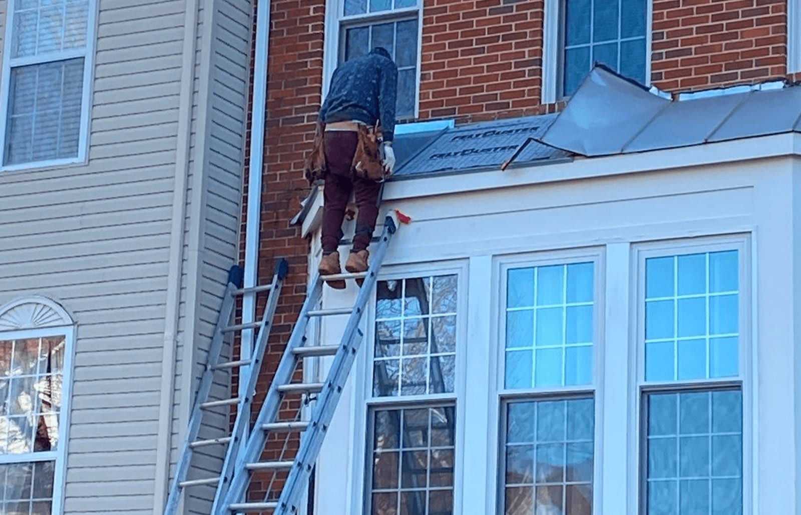 Roofsimple worker on roof installing new roofing system for John Sura