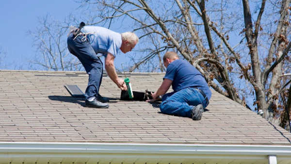Two roofers installing roofing shingles