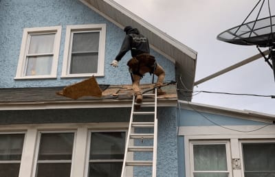 Roofsimple worker on roof installing new roofing system for Benjamin Ranieri 