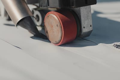 Roofer heat-welding TPO seams with a hand-held welder