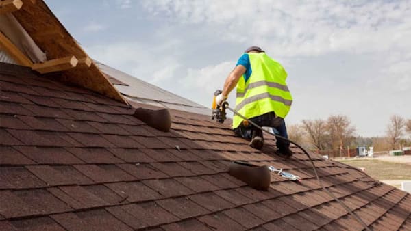 Roofer fixing shingles on a roof