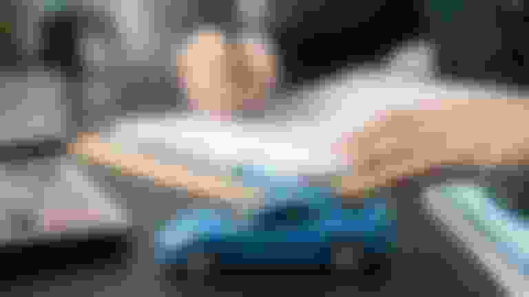 A toy car on a desk with a calculator and clipboard.