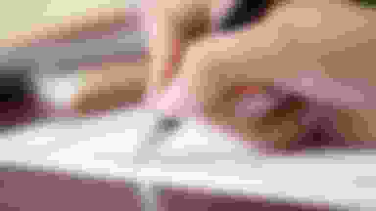 A woman's hand, holding a pen, checking boxes on a piece of paper.