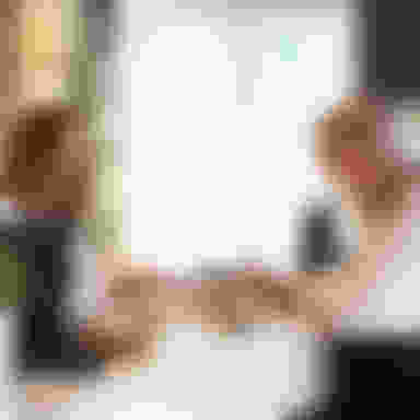 Two women at a concierge desk with paper and pen and a bell.