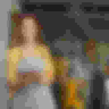 Female business owner in yellow shirt standing near a restaurant door.