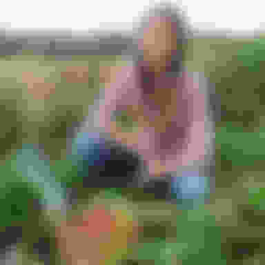 person kneeling in garden with basket full of fresh veggies