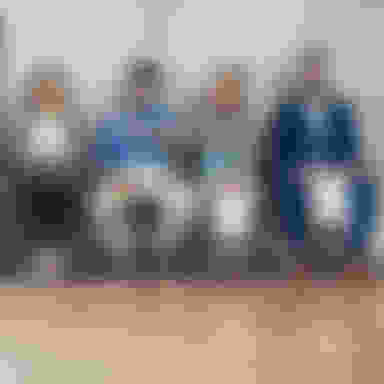 several people sitting in a row of chairs against a brick wall waiting and all holding paper such as an application or resume