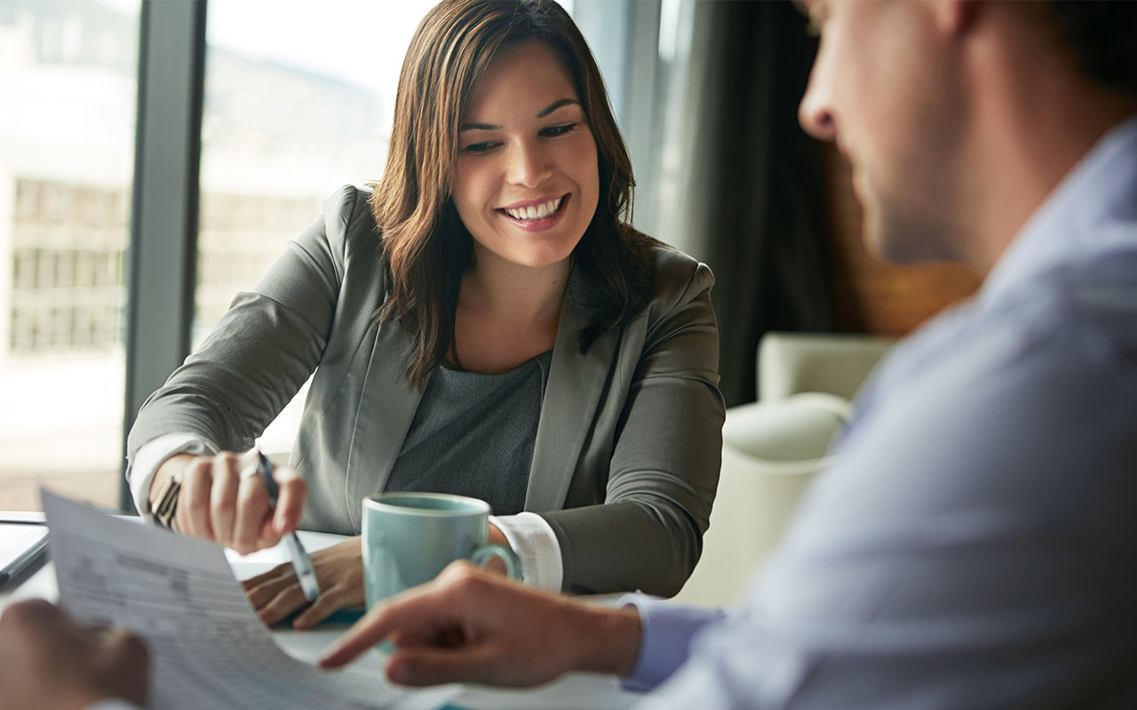 A man and woman pointing and discussing a sheet of paper.