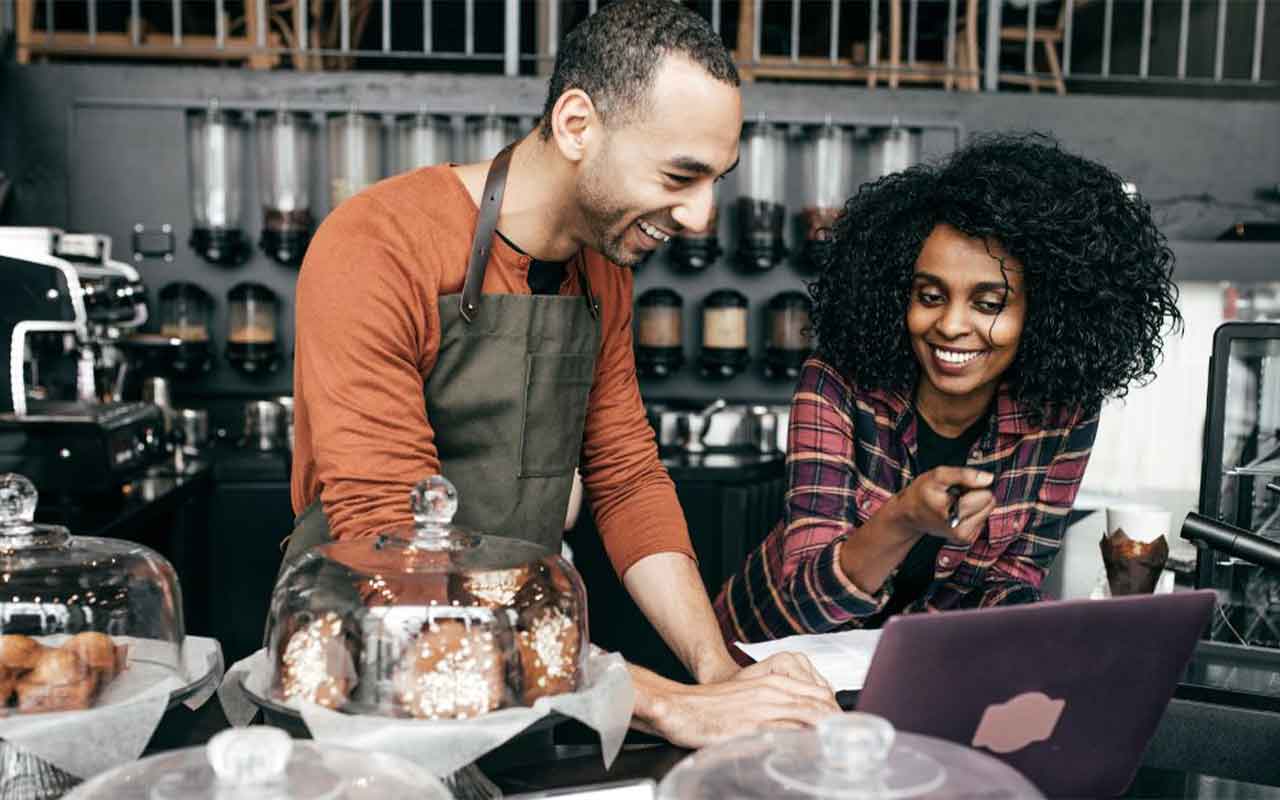 Baristas collaborating on a laptop.
