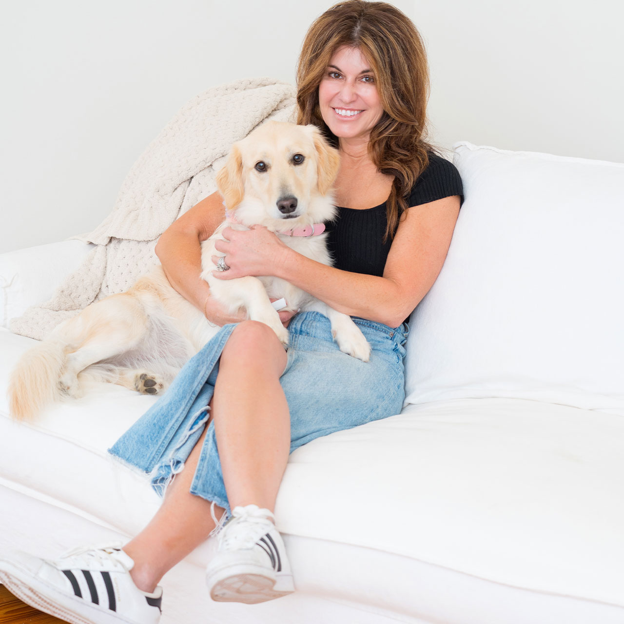 A woman sitting on a couch, holding her dog.