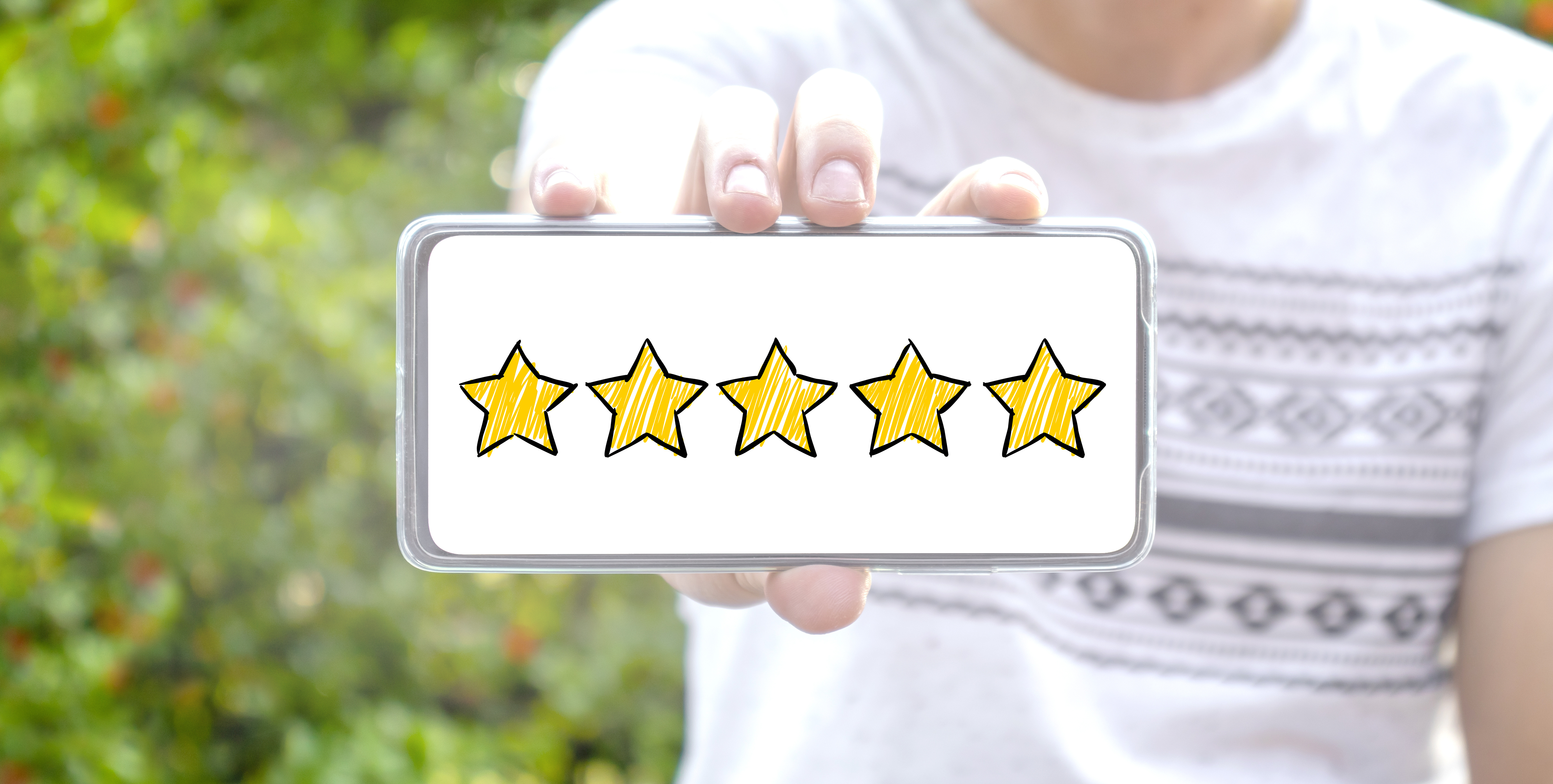 A person holding a mobile phone showing five golden stars.