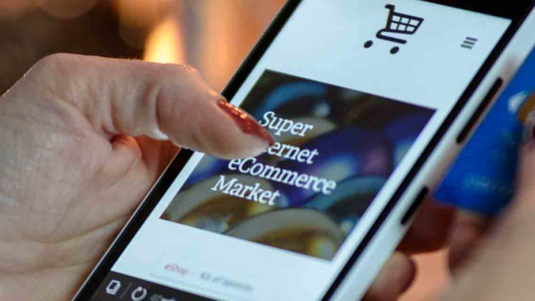 A woman's hand holding a mobile phone that shows an e-commerce site on the screen.