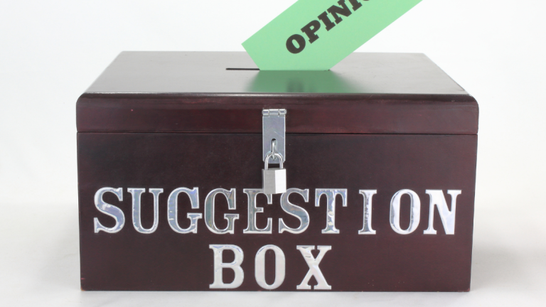 Suggestion box with someone placing a card inside it.