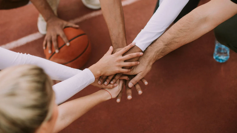 People putting their hands in a circle on a basketball court.