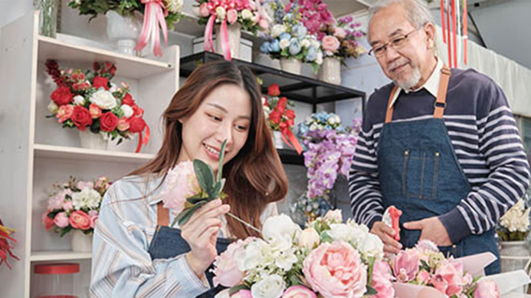 A man and woman working in a flower shop.
