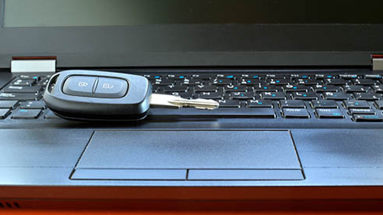 A car key sitting on the keyboard of a laptop.