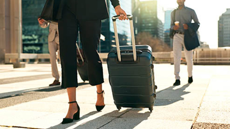 A business woman puling a rolling suitcase.