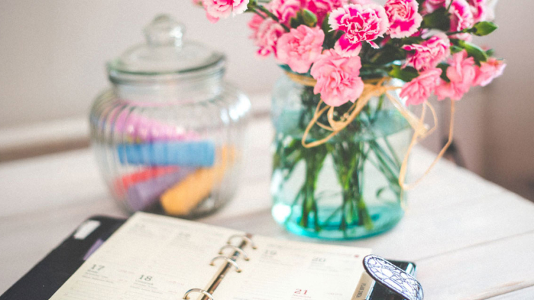 Flowers, a jar with chalk and an open calendar on a table.