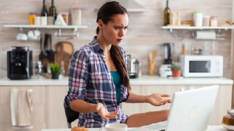 frustrated woman sitting in front of laptop in kitchen