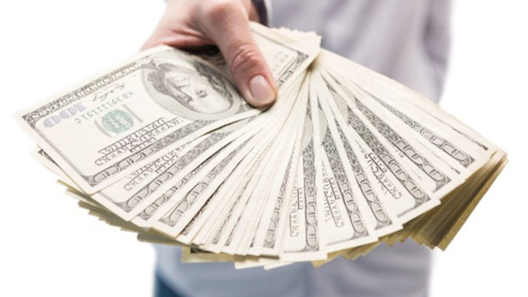 A man holding $100 bills fanned out in his hand.