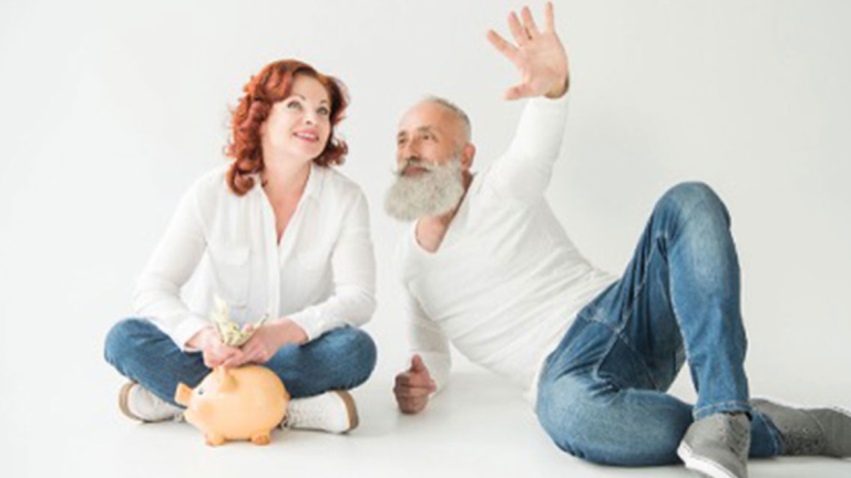 A man and woman sitting next to a piggy bank with the woman holding money.