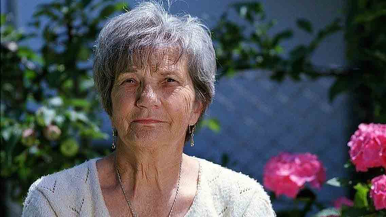 older woman sitting next to flowers