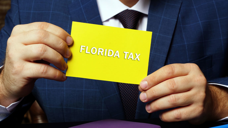 A man in a business suit holding a card that says "Florida Tax."