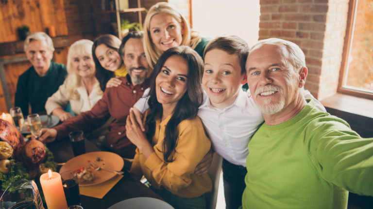 A large family gathered around the thanksgiving table taking a selfie.