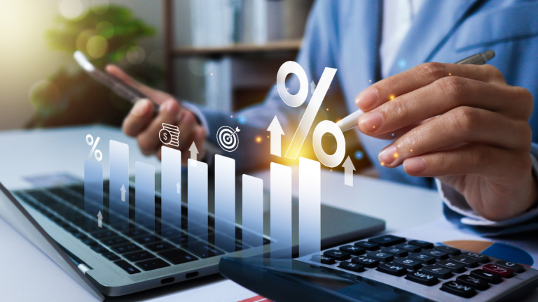 A small business owner looking at his computer and phone reviewing financial data.