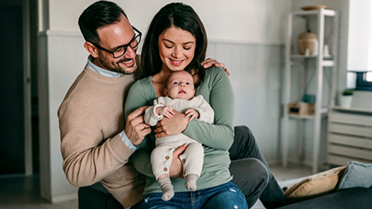 A man, woman and baby on a sofa.