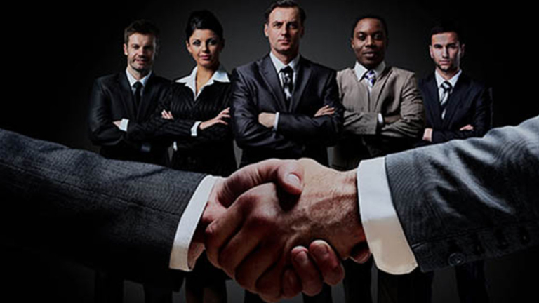 Business professionals with two people shaking hands.