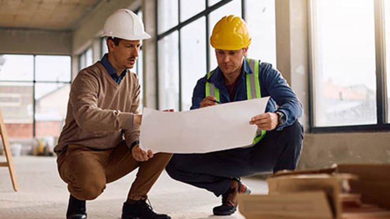 Two workers in hard hats looking at a schematic.