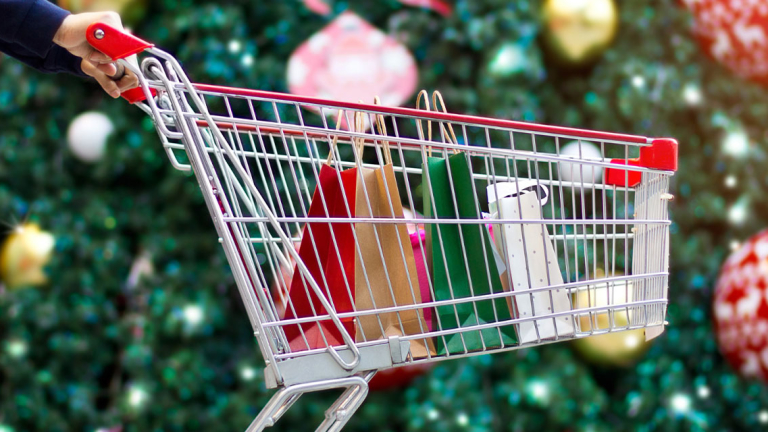 Hands pushing a shopping cart with gift bags.