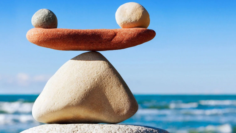 Rock balancing on top of each other with water and waves in the background.