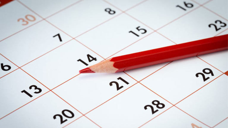 A calendar with a red pencil laying on it.