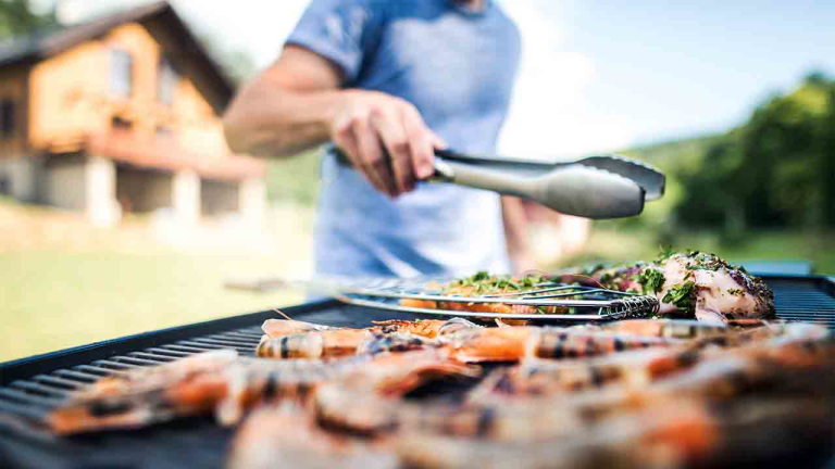 Unrecognizable man cooking seafood on a barbecue grill in the backyard.