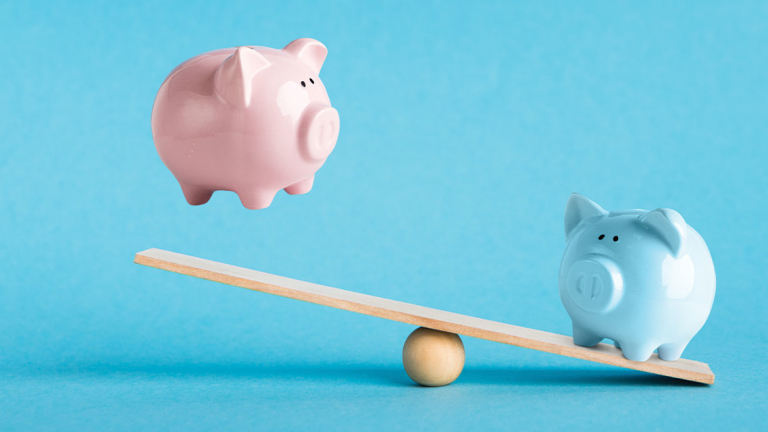 Piggy banks balancing on a piece of wood.