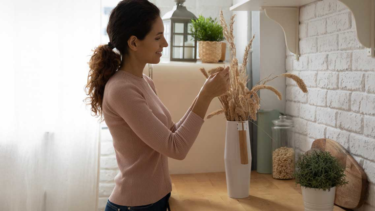 A woman touching a vase with flowers in it.