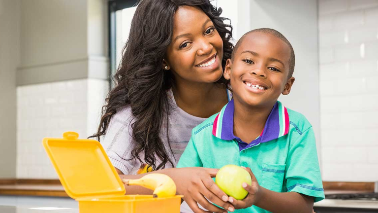 A woman and child smiling with an open lunch box in front of them.