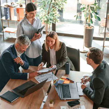 Business professionals in a conference room, gathered around the table.