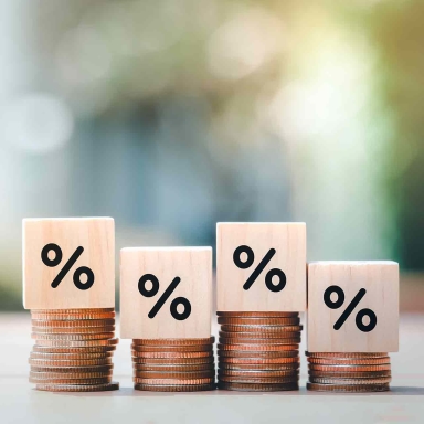 Interest rate finance and mortgage rates. Wooden block with percentage sign on many level of stack of coin.