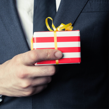 business person in suit holding small wrapped gift in hand