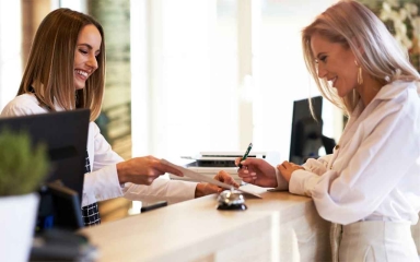 A business professional speaking with a customer of over a desk.