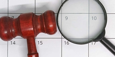 gavel and magnifying glass over calendar