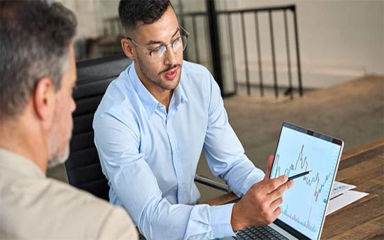 man showing graph to another man on a computer screen