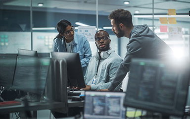 Three professionals gathered around a computer in an office.