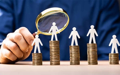 man holding magnifying glass over paper cutouts of a person standing on top of coins